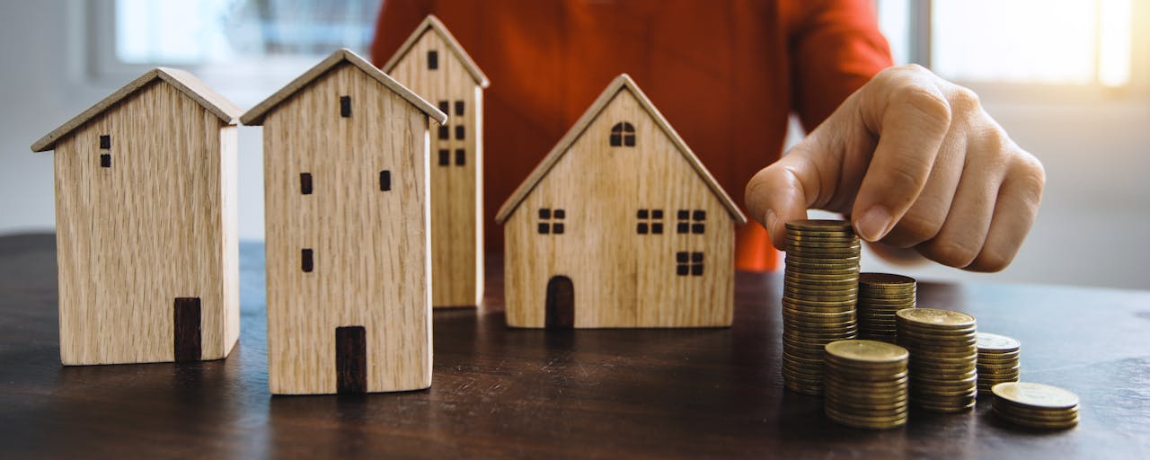services-02 Planning investments with stacked coins and model houses on a table.