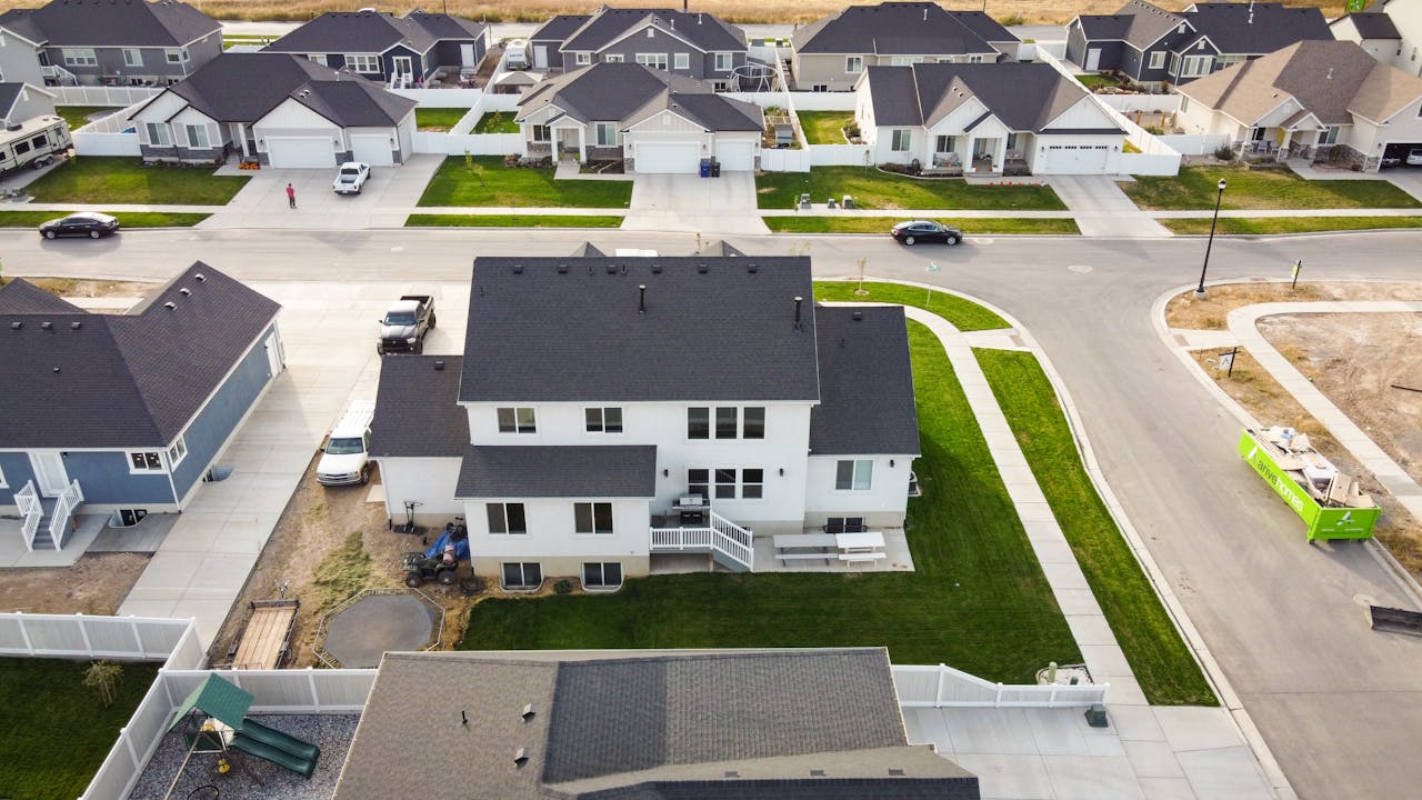 about-img Aerial shot of a residential area in Spanish Fork, Utah, showcasing modern homes and green lawns.