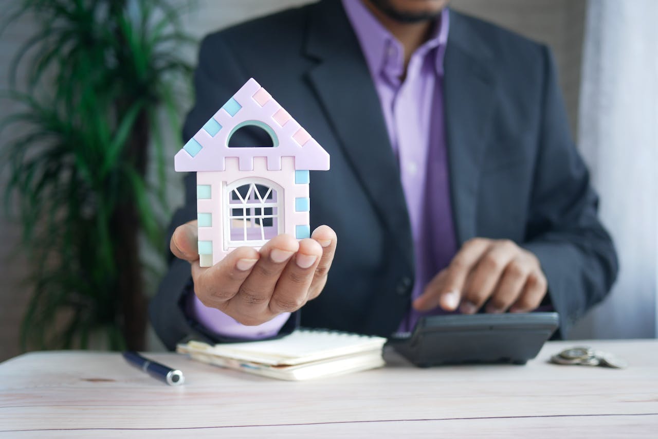 services-img Businessman in suit holds model house, calculates real estate investments.